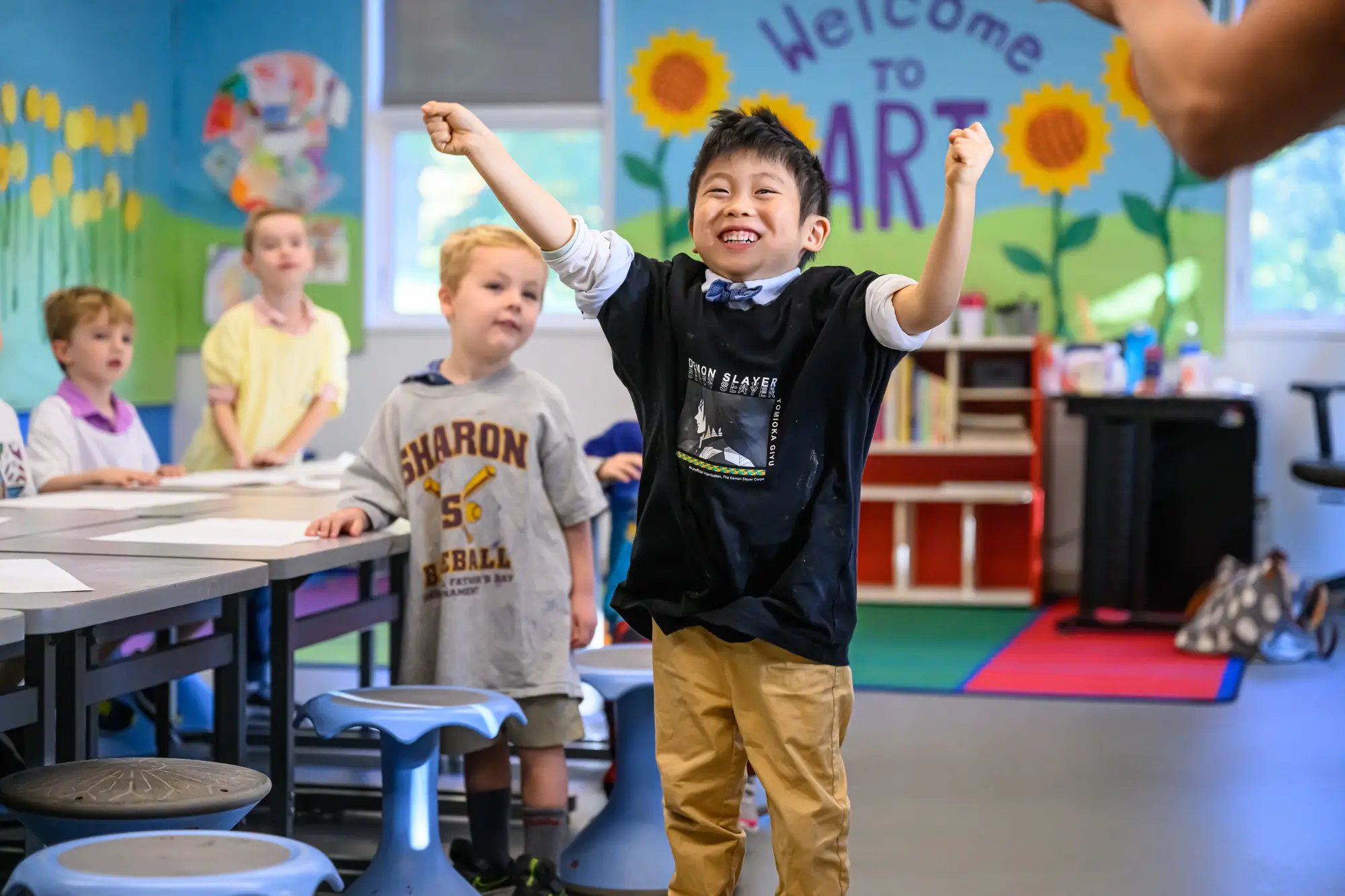 A boy has his arms up in celebration in class