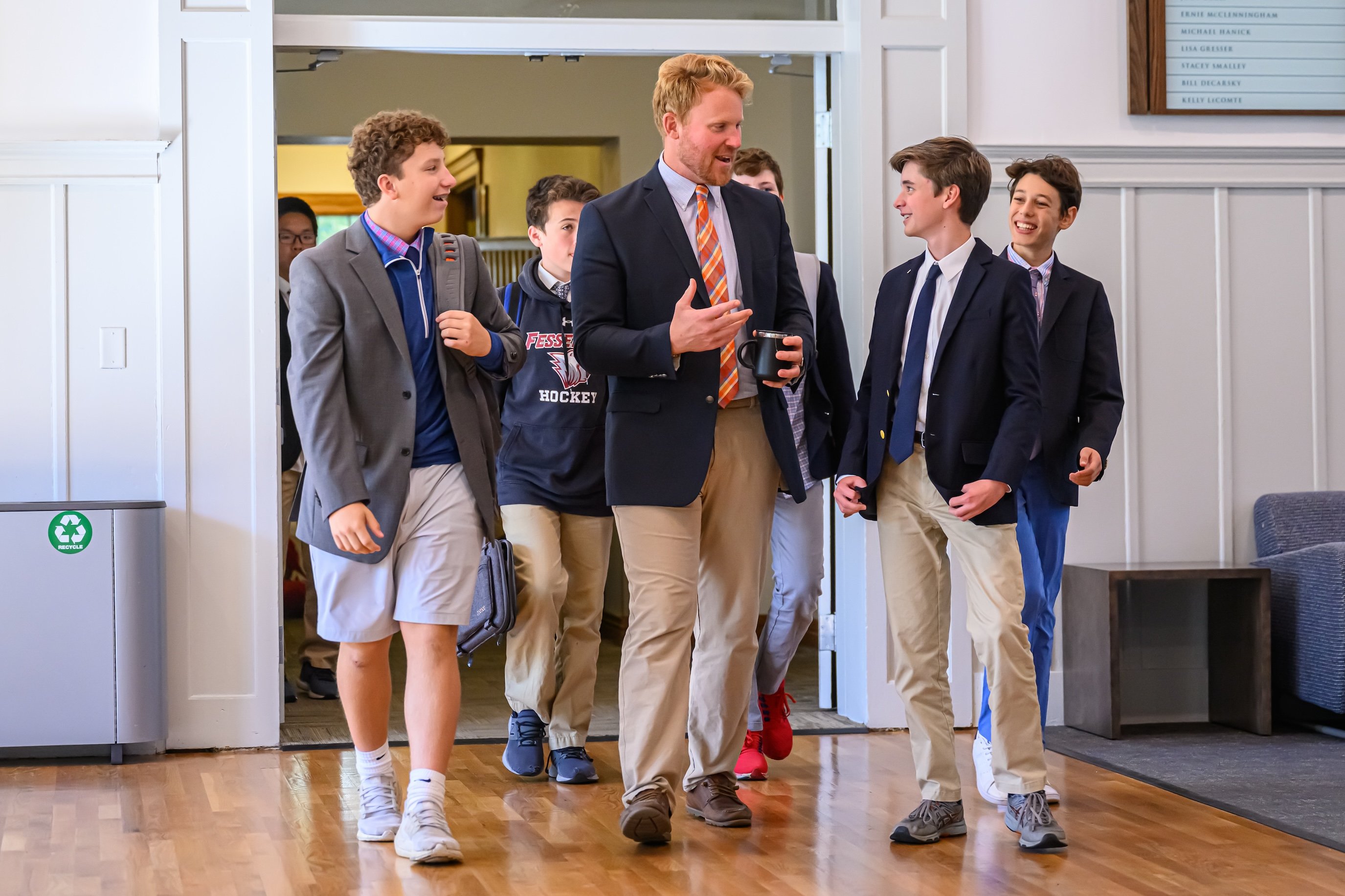  a teacher at The Fessenden School, walking and talking to students as they enter a classroom.