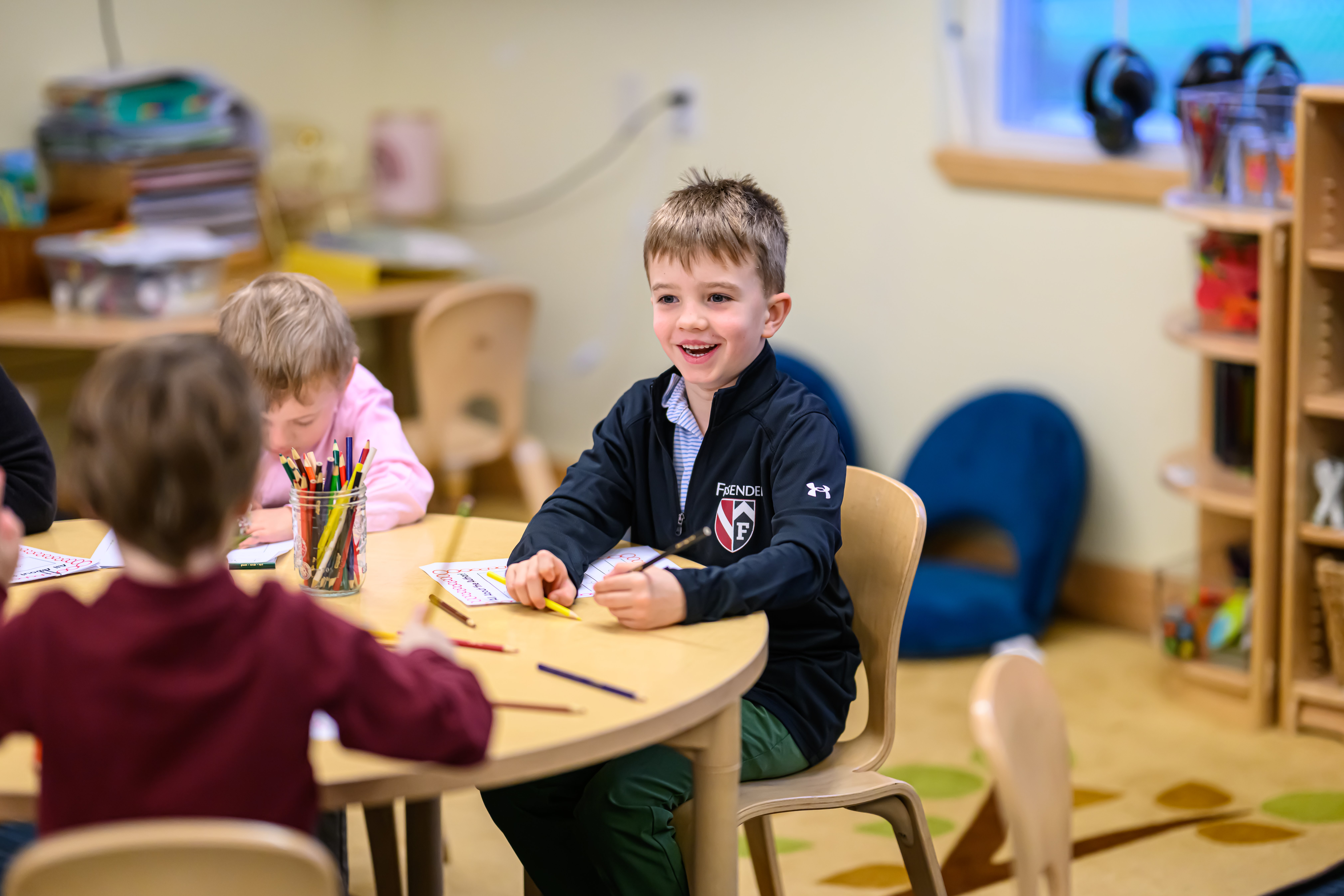 A pre-k student laughing and coloring during class at The Fessenden School in West Newton, MA.