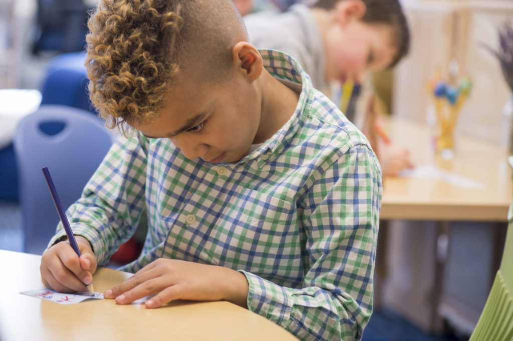 a pre-k student at The Fessenden School writing a note during class.