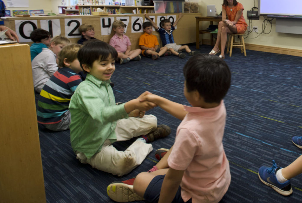 Pre-K students at The Fessenden School shaking hands and playing a game during class.