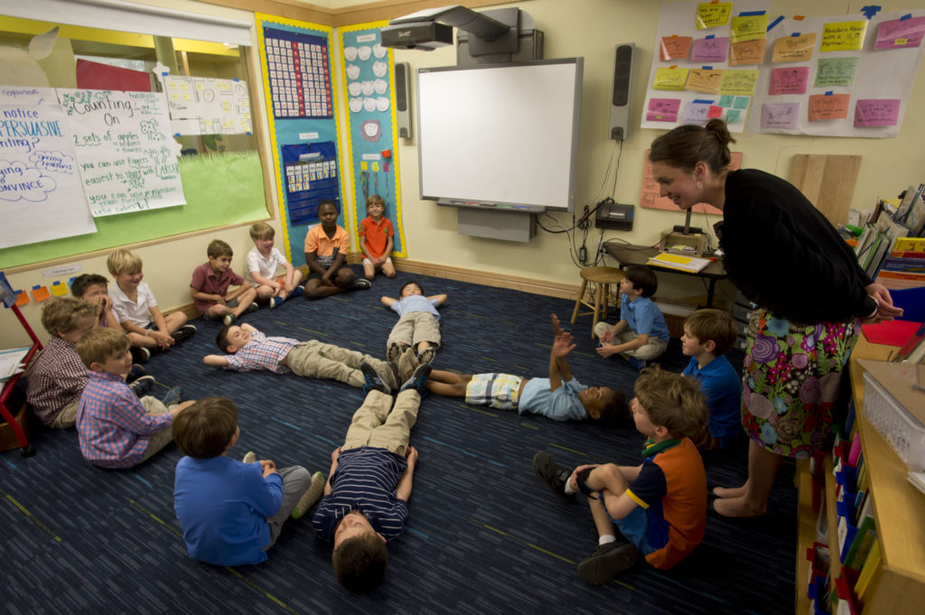 Students in a pre-K classroom at The Fessenden School participating in an activity and listening to the teacher.