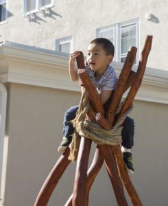 A Pre-K student from The Fessenden School climbing a wooden sculpture during class.