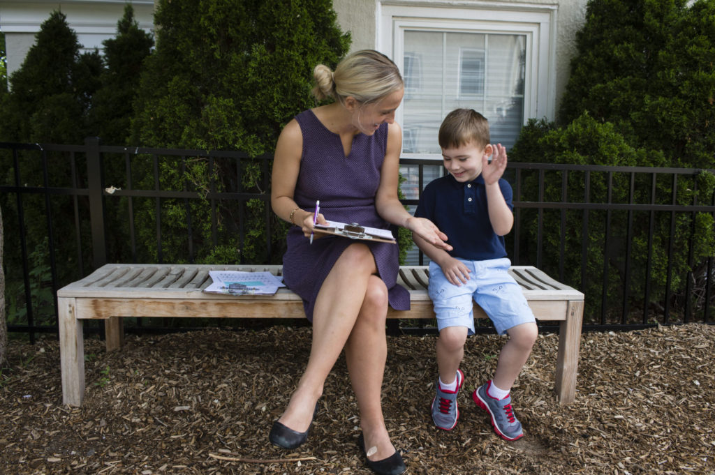 A teacher and a pre-k student at The Fessenden School sitting outside and giving a high-five.