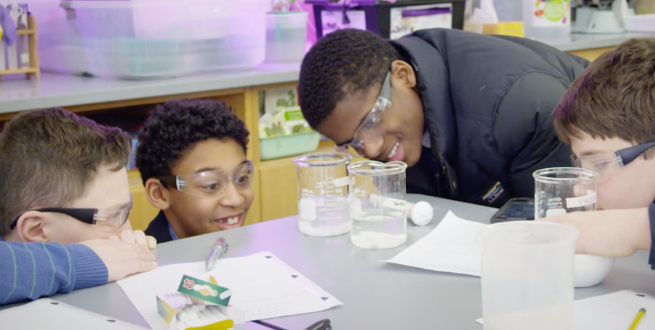 Four middle school students at The Fessenden School looking at glass lab beakers during science class.