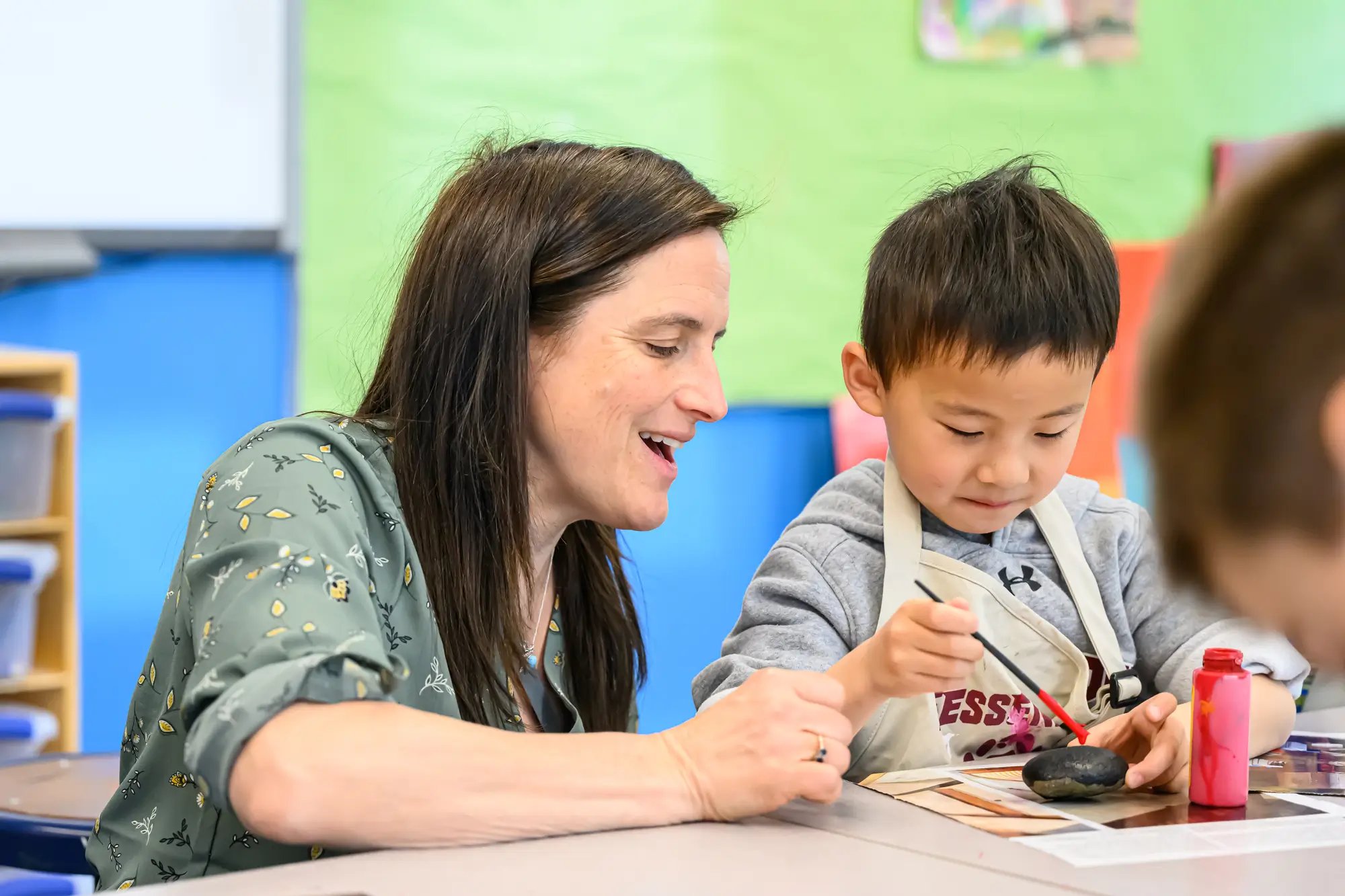 A young boy paints with his art teacher