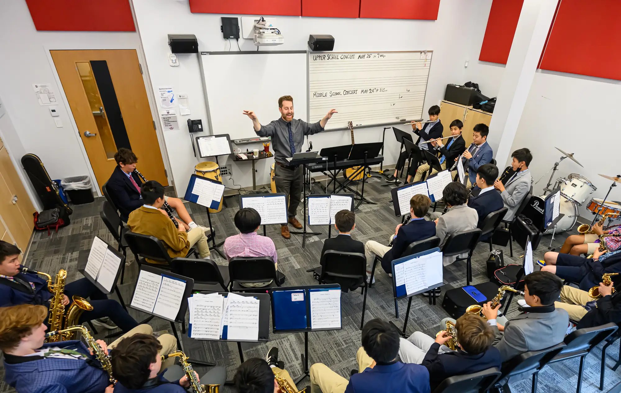 A male conductor leads a small band of middle school students