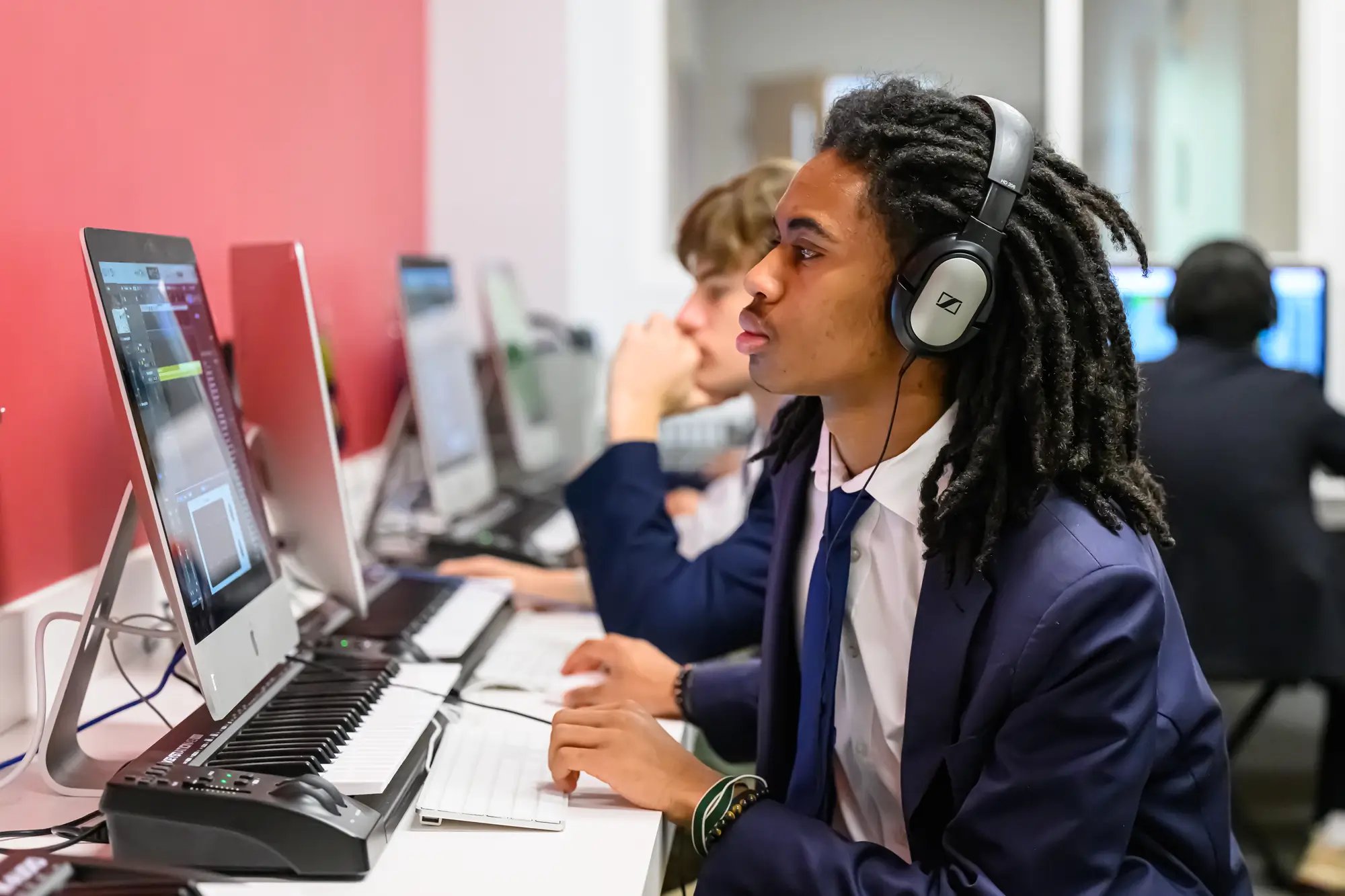 A teenage boy works on a midi keyboard during a music class