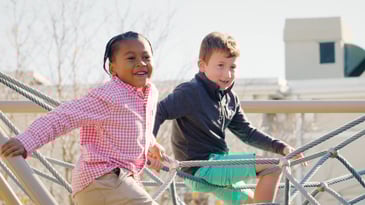 Preschool student smiling and climbing on a rope structure at Fessenden, a private school near Boston.