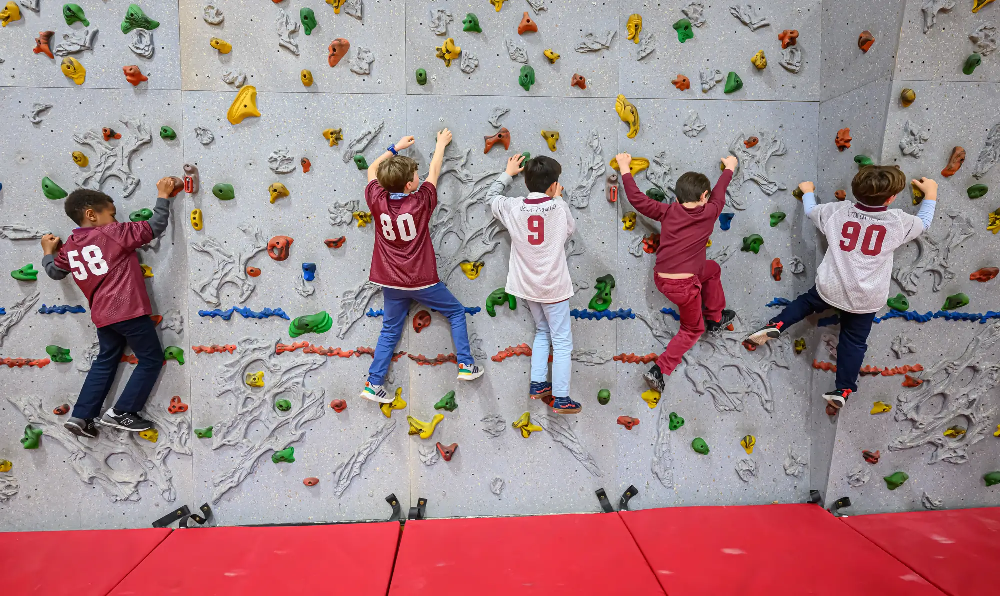 Young boys play on a climbing wall at a gym