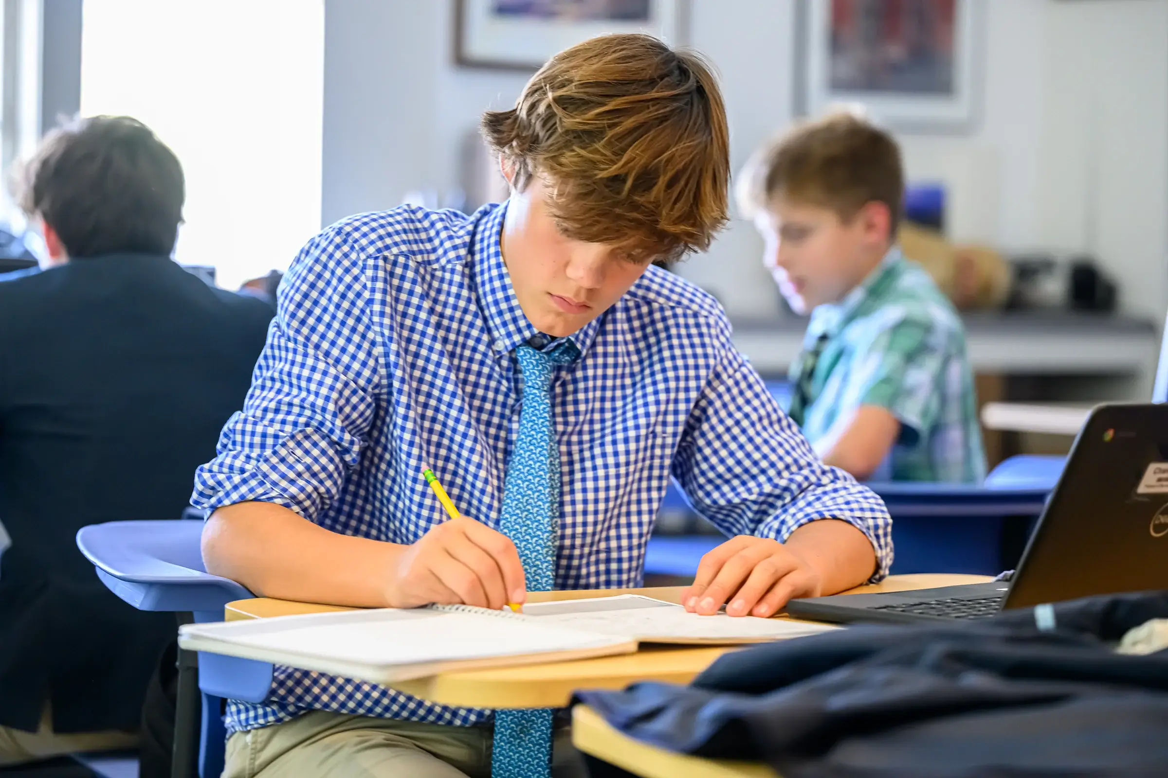 Boy writing at desk in classroom